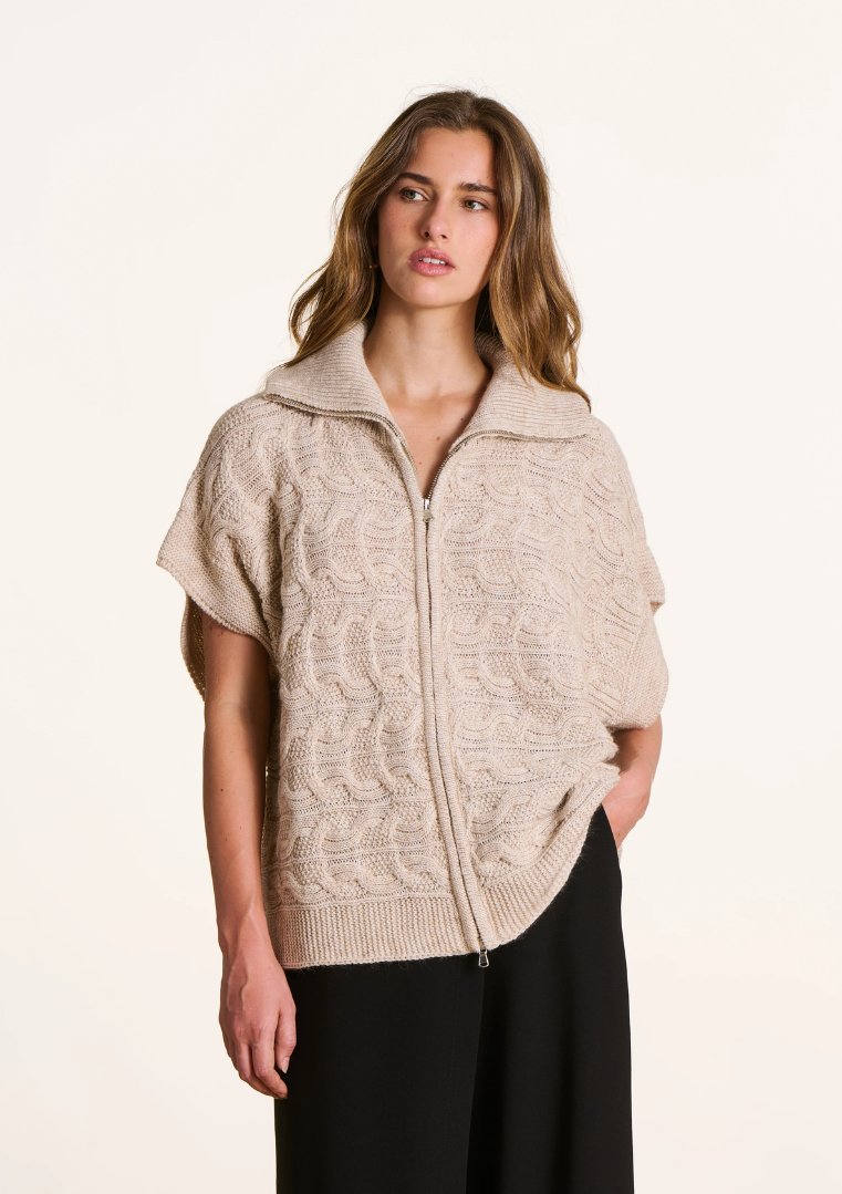 Femme portant un gilet oversize torsadé écru à manches courtes tombantes, col camionneur et fermeture zippée.
Ref. FK-GI-ELISE-C_266 – La Fée Maraboutée
