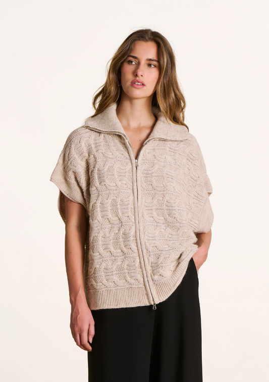 Femme portant un gilet oversize torsadé écru à manches courtes tombantes, col camionneur et fermeture zippée.
Ref. FK-GI-ELISE-C_266 – La Fée Maraboutée