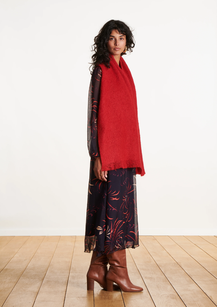 Femme de profil portant une écharpe en mohair rouge longue sur une robe fluide imprimée et des bottes marron.
FI-AT-ZLARINA_727 - La fee maraboute