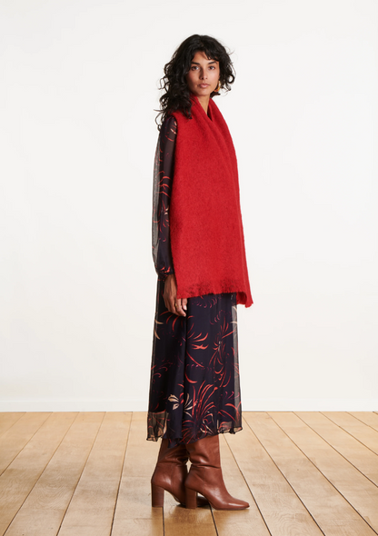 Femme de profil portant une écharpe en mohair rouge longue sur une robe fluide imprimée et des bottes marron.
FI-AT-ZLARINA_727 - La fee maraboute