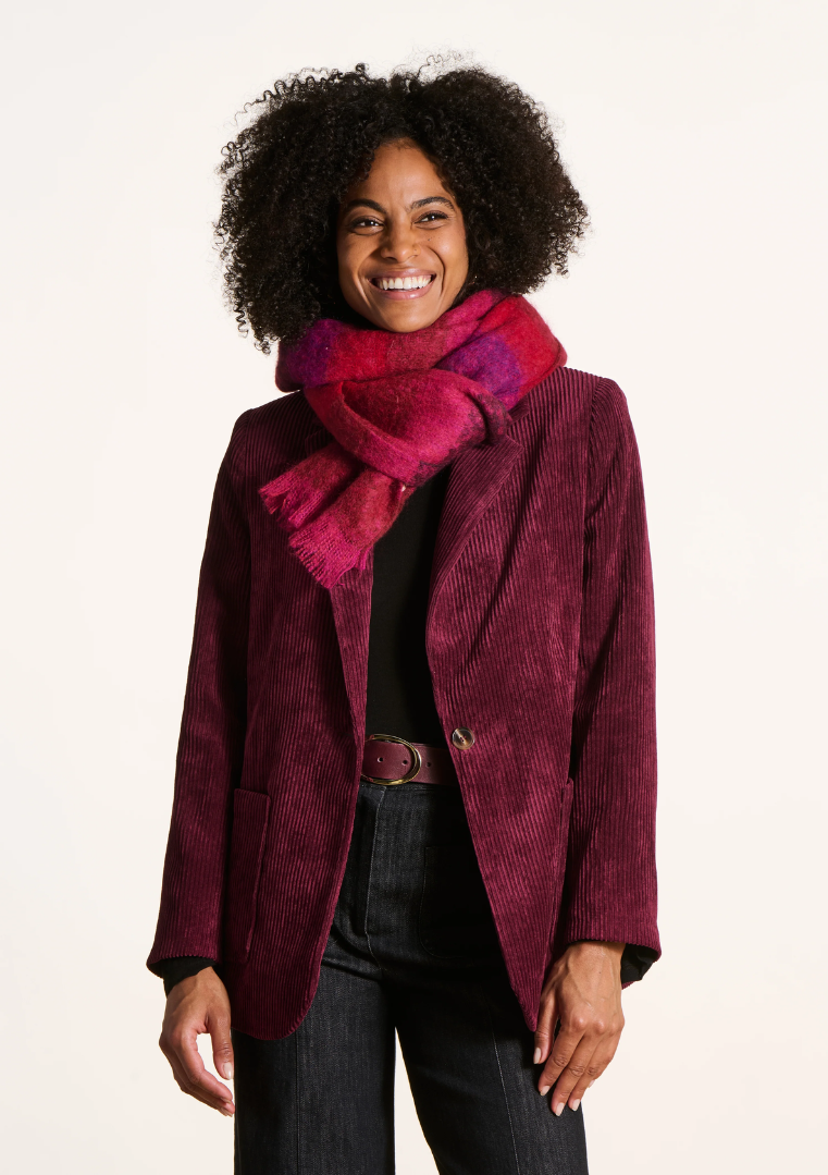 Femme souriante portant une écharpe rayée rouge et violette en mohair, avec une veste en velours côtelé bordeaux.
FK-AT-EZEKIEL_727 -_La_fee_maraboute