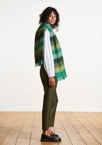 Vue de profil d’une femme portant l’écharpe rayée verte en mohair avec un pantalon vert olive.
FK-AT-EZEKIEL_709 - La fee maraboute